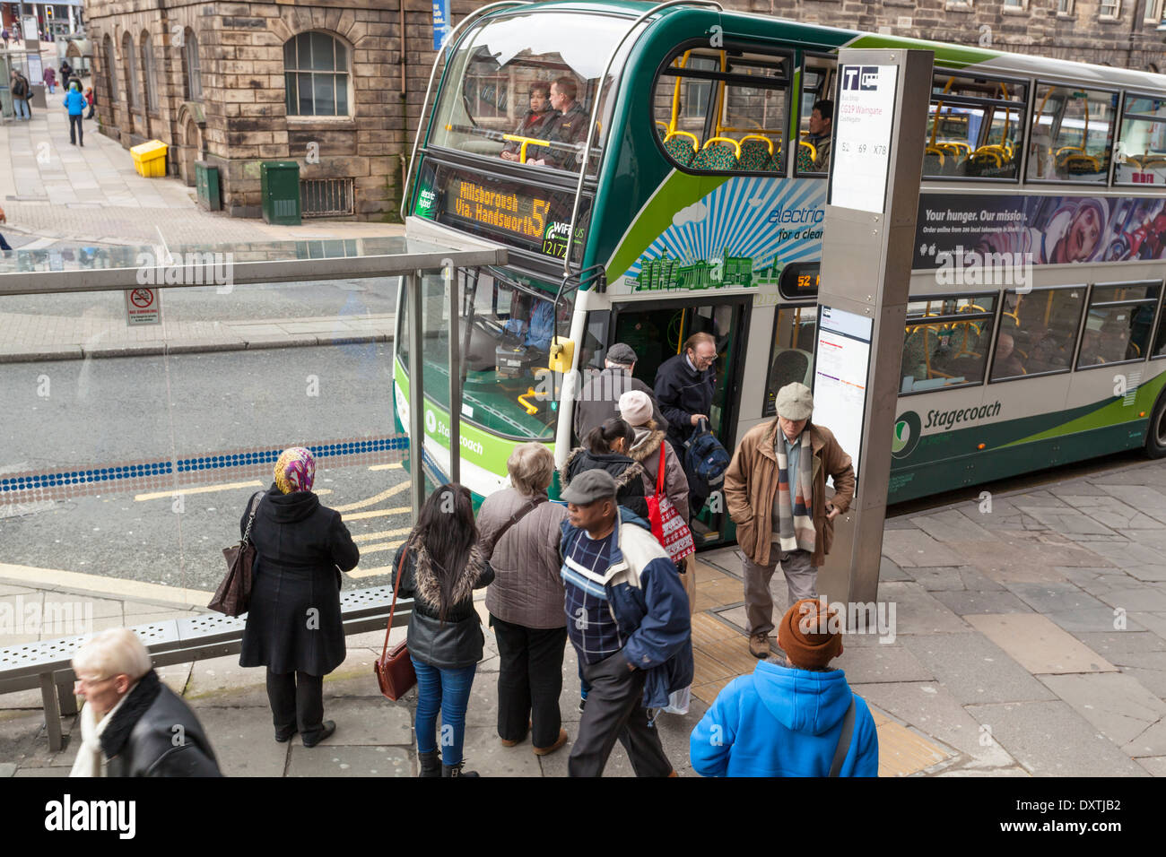 Mit den öffentlichen Verkehrsmitteln. Menschen, die darauf warteten, an einer Bushaltestelle während Passagiere aussteigen sind ein Bus, Sheffield, Yorkshire, England, Großbritannien Stockfoto