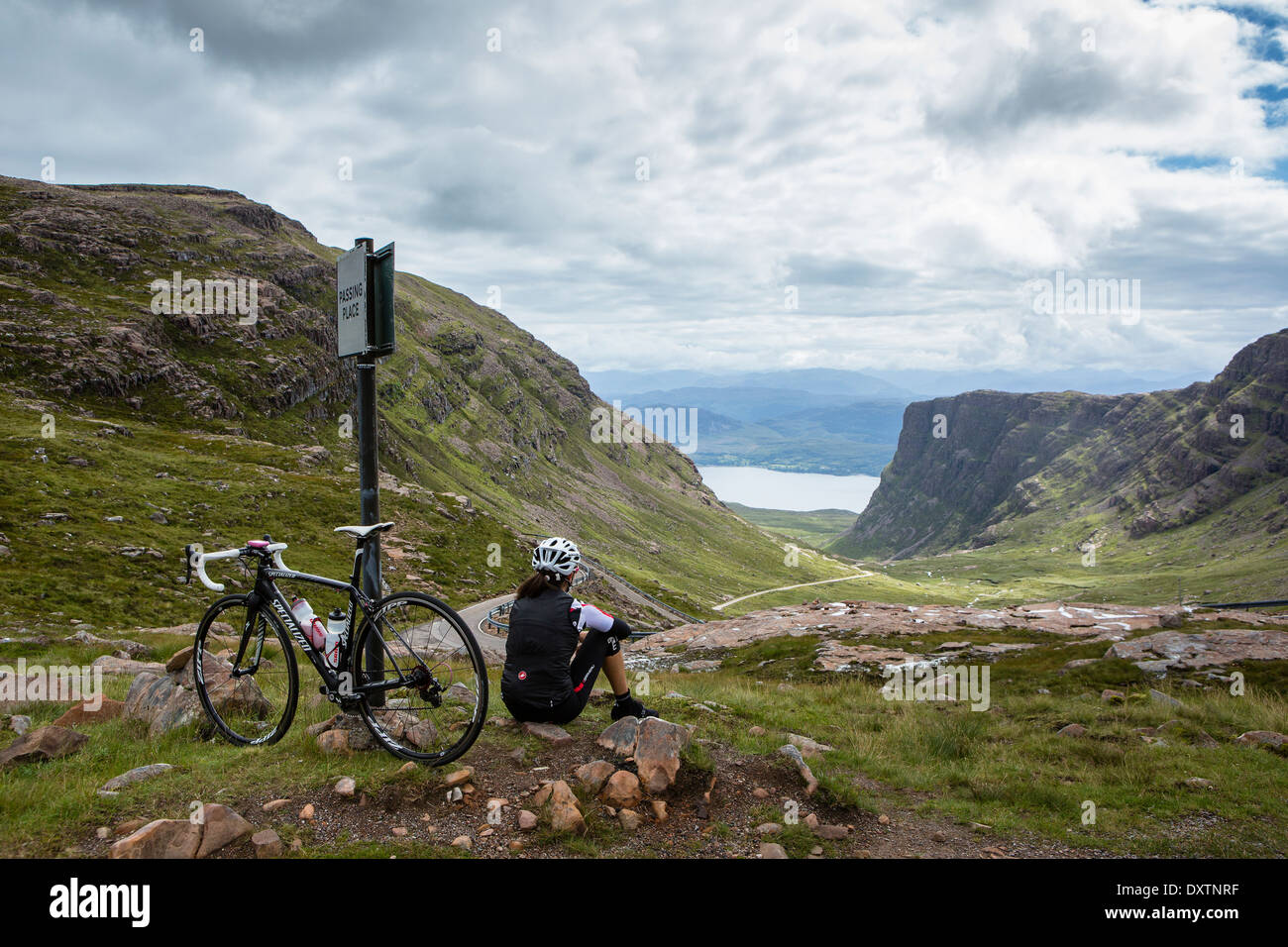 Ein Radfahrer liegt teilweise bis Großbritanniens längsten Straße klettern in Lochcarron Schottland. Rückblickend auf die Leistung Stockfoto
