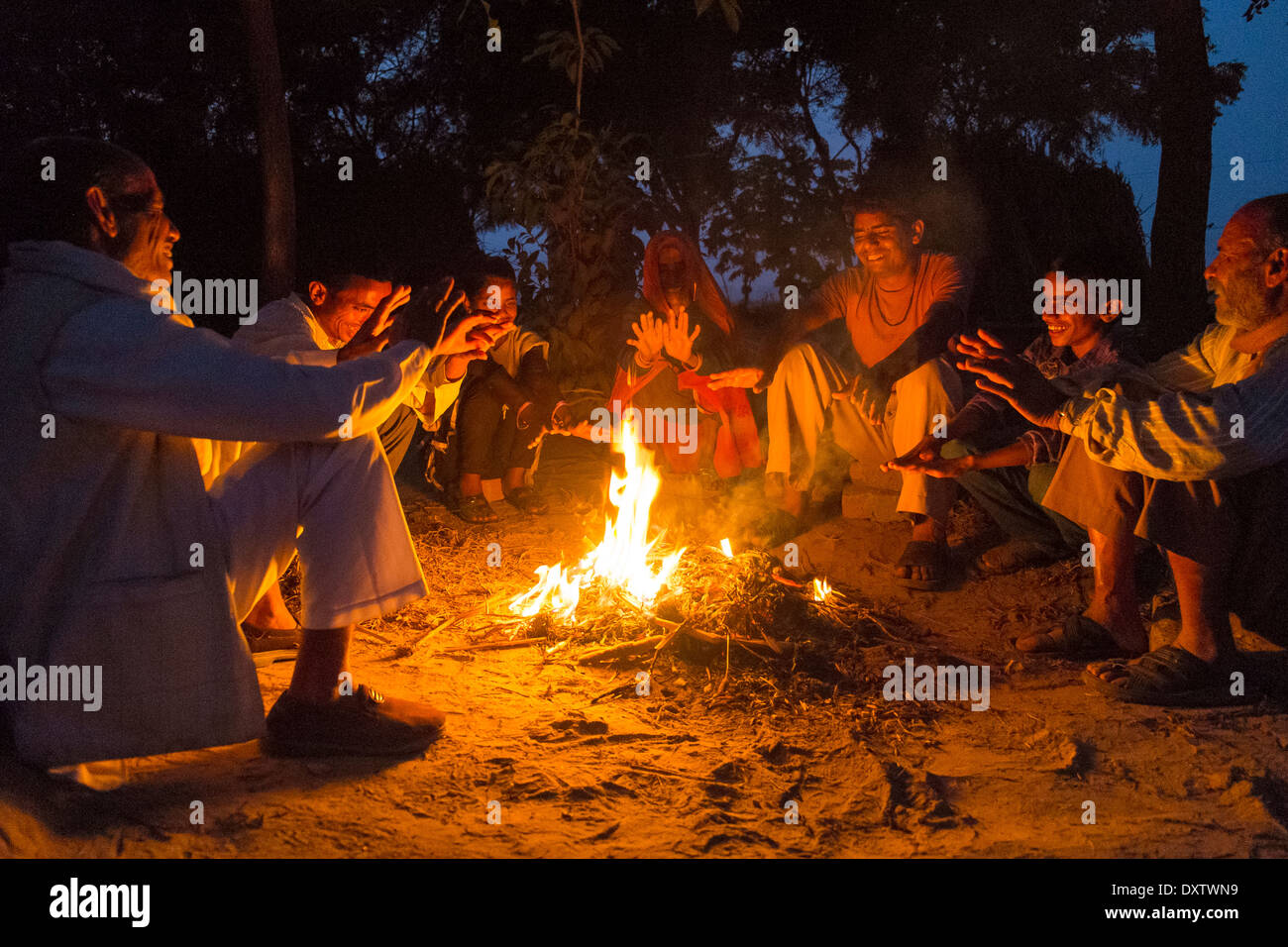 Indien, Uttar Pradesh, Familie sitzt um offenes Feuer in der Abenddämmerung Stockfoto