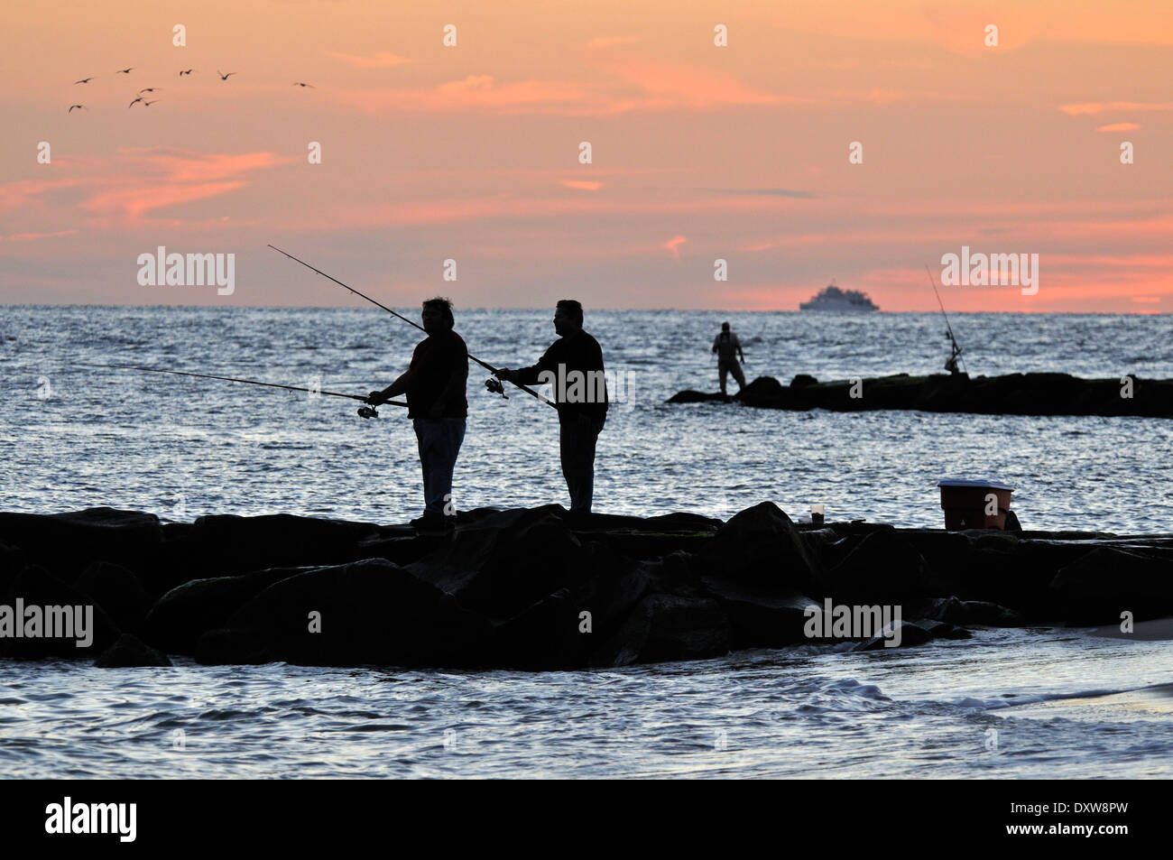 Männer Angeln am Strand bei Sonnenuntergang in Cape May, NJ, USA Stockfoto