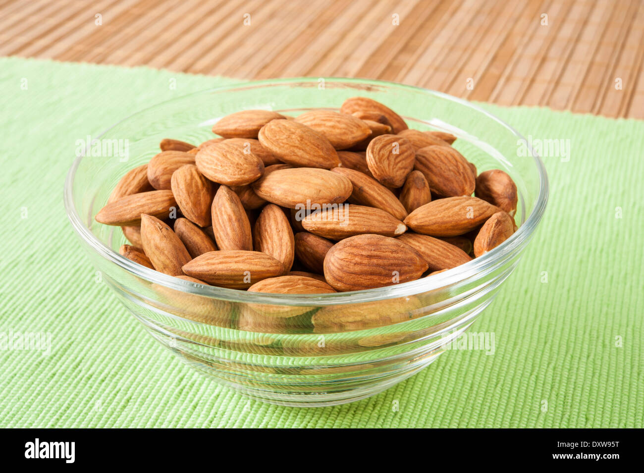 Schüssel mit Mandeln in eine Glasschale auf einer grünen Matte Stockfoto
