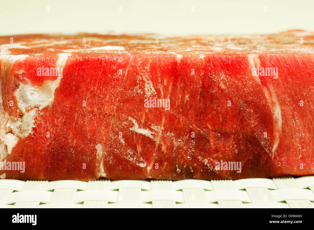 Gefrorenes Fleisch. Gefrorenes Rindfleisch schmilzt auf grünem Hintergrund. Stockfoto