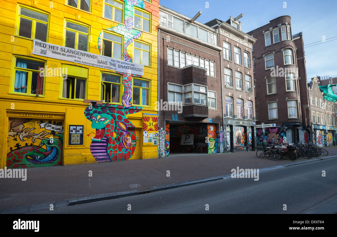AMSTERDAM, Niederlande - 19. März 2014: Gelbe Snakehouse Fassade mit bunten Graffiti und Petition drauf Stockfoto