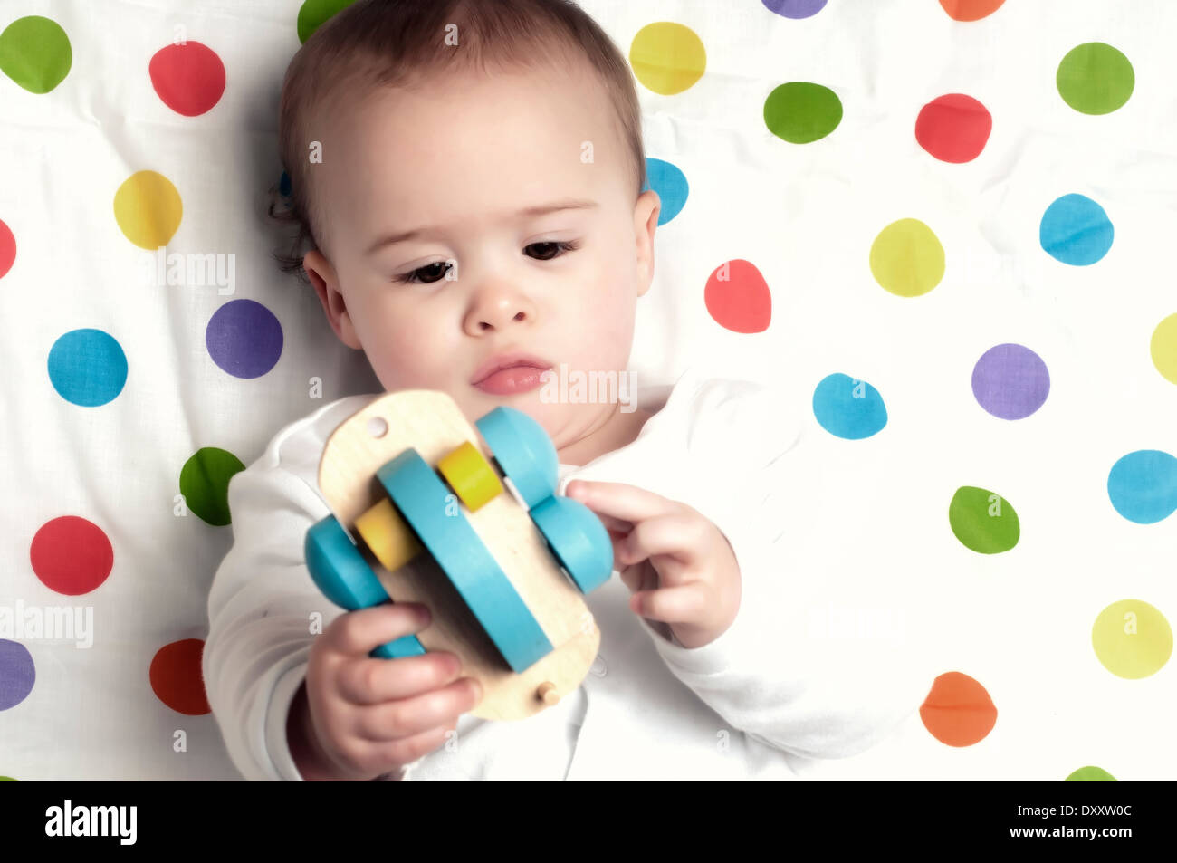 Ein Jahr alt Babyjungen auf fleckigen Decke mit Holzeisenbahn spielen Stockfoto