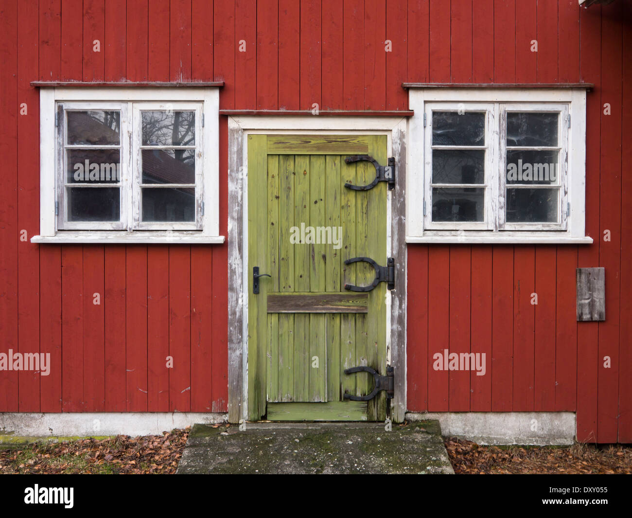 Grüne Tür mit lustigen Hufeisen förmigen Scharniere auf alten roten Hof Nebengebäude, weiße Fensterrahmen, Moss, Norwegen Stockfoto