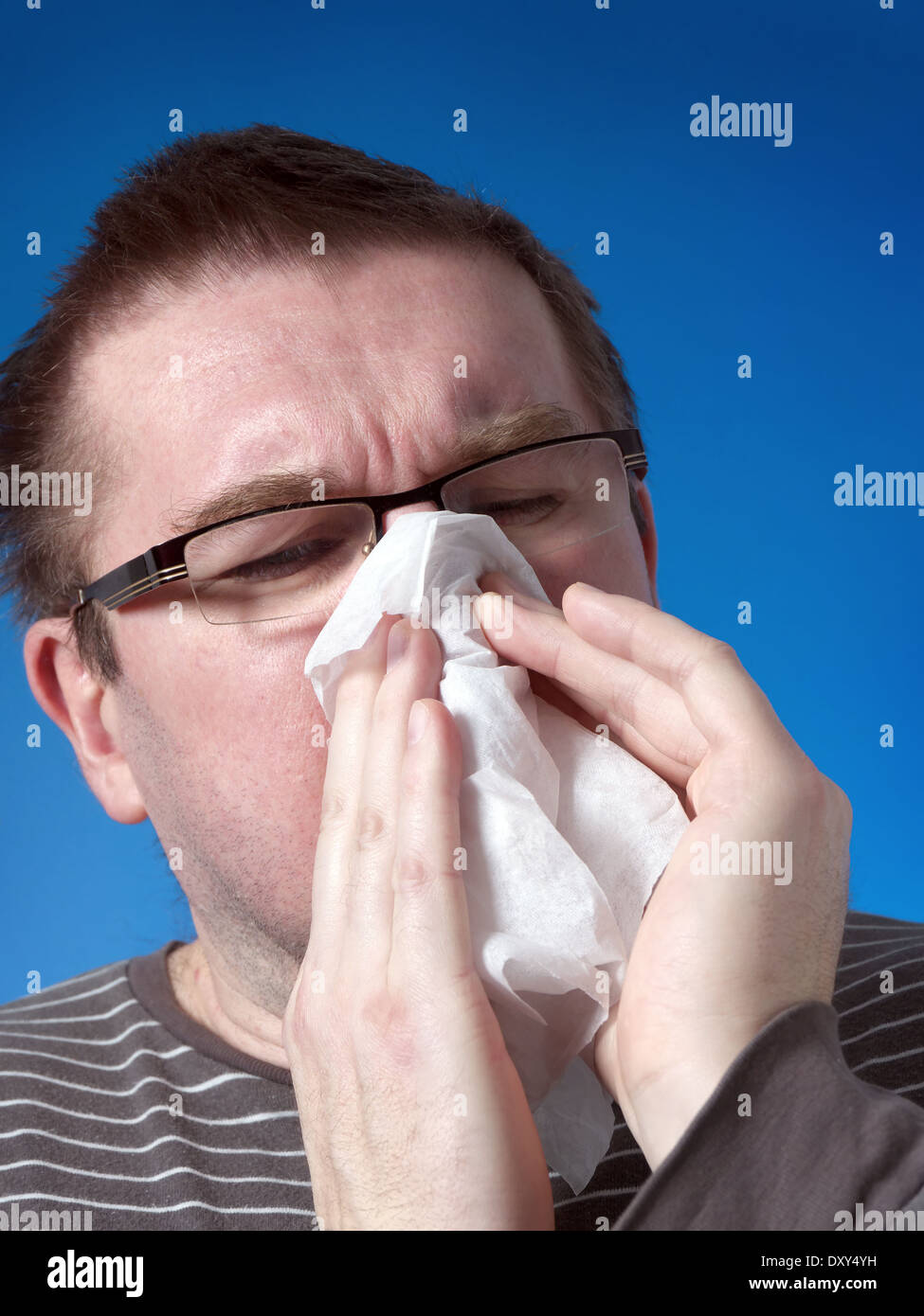 Junger Mann bläst seine Nase mit Papiertuch Stockfoto