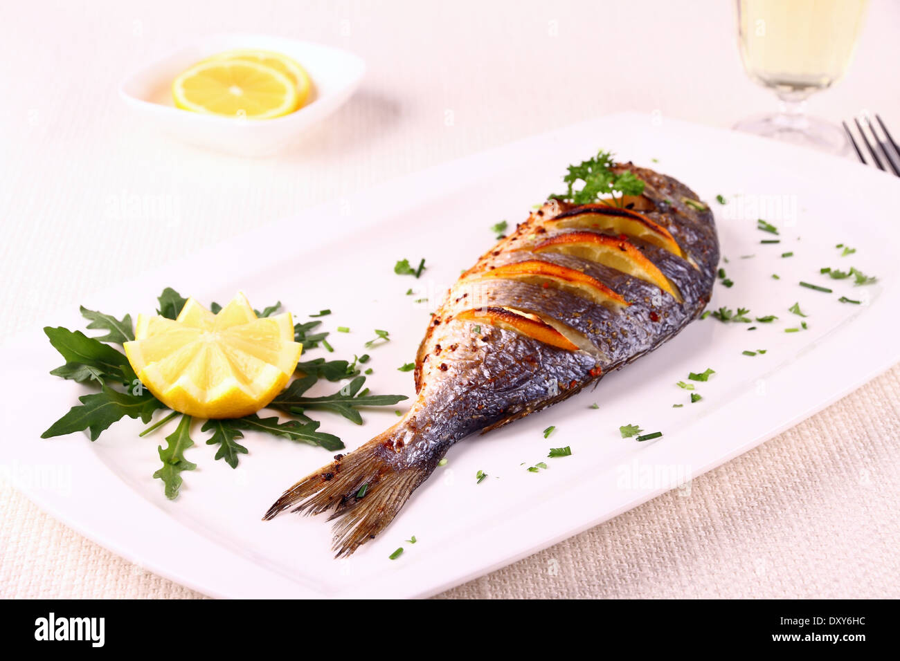 Gegrillte Dorade Fisch, Zitrone, Rucola auf weißen Teller, horizontale Stockfoto