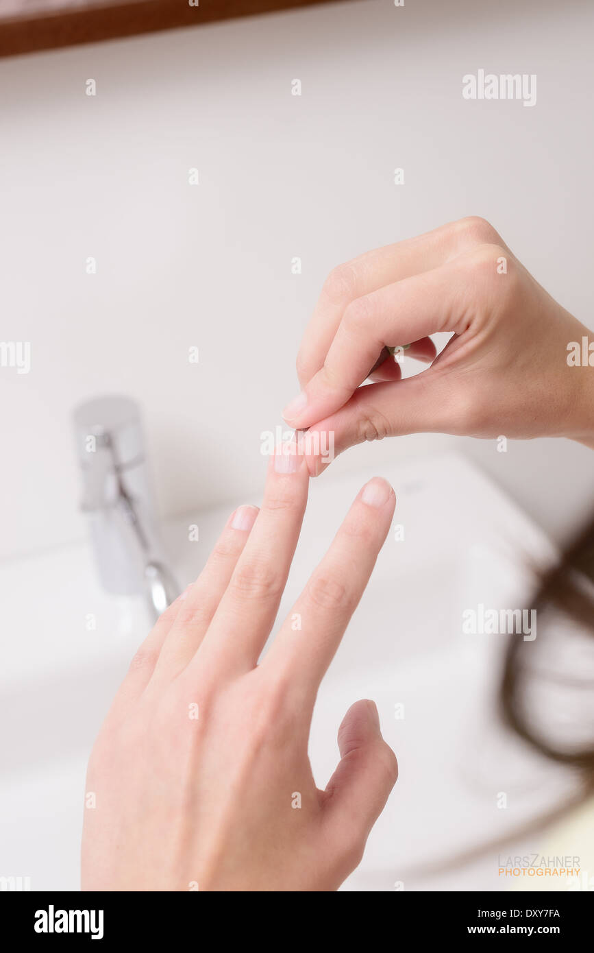 Frau, die Gestaltung und Reinigung ihrer Nagelhaut auf ihre Fingernägel in einem Gesundheit, Hautpflege und Schönheit-Konzept mit einem spitzen Werkzeug Stockfoto
