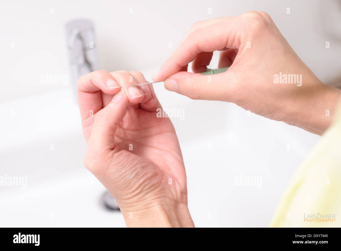 Frau, die Gestaltung und Reinigung ihrer Nagelhaut auf ihre Fingernägel in einem Gesundheit, Hautpflege und Schönheit-Konzept mit einem spitzen Werkzeug Stockfoto