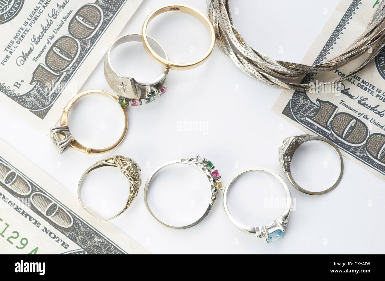 Goldschmuck auf weiß mit 100-Dollar-Scheine am Rand, Bargeld für Gold. Stockfoto