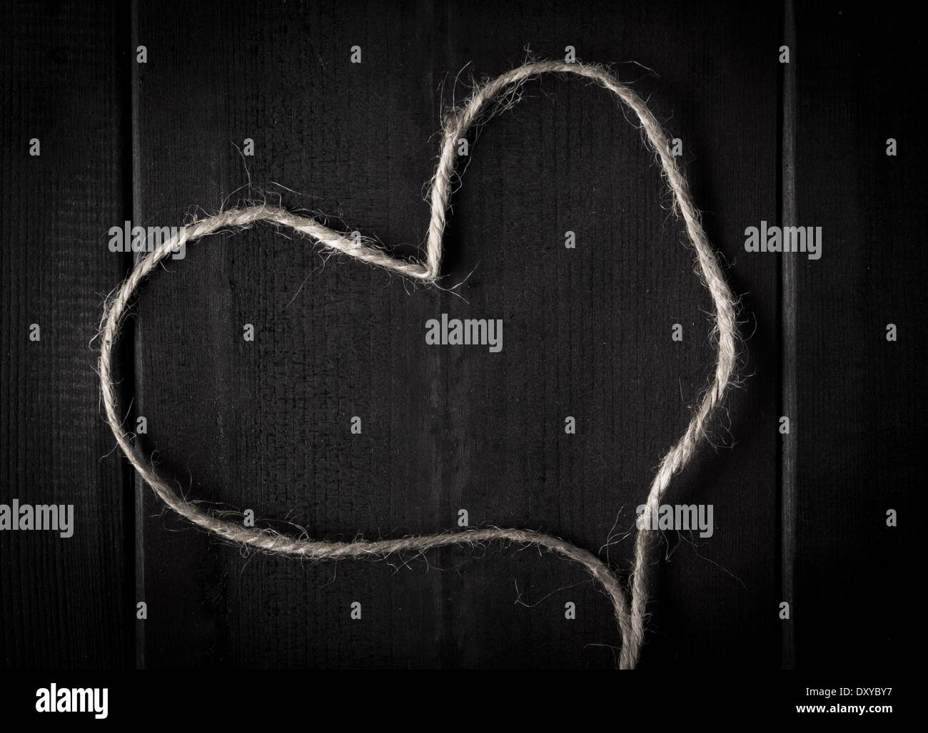 Nahaufnahme von Hanf-Garn oder Schnur in Form eines Herzens auf dunklem Holz Stockfoto