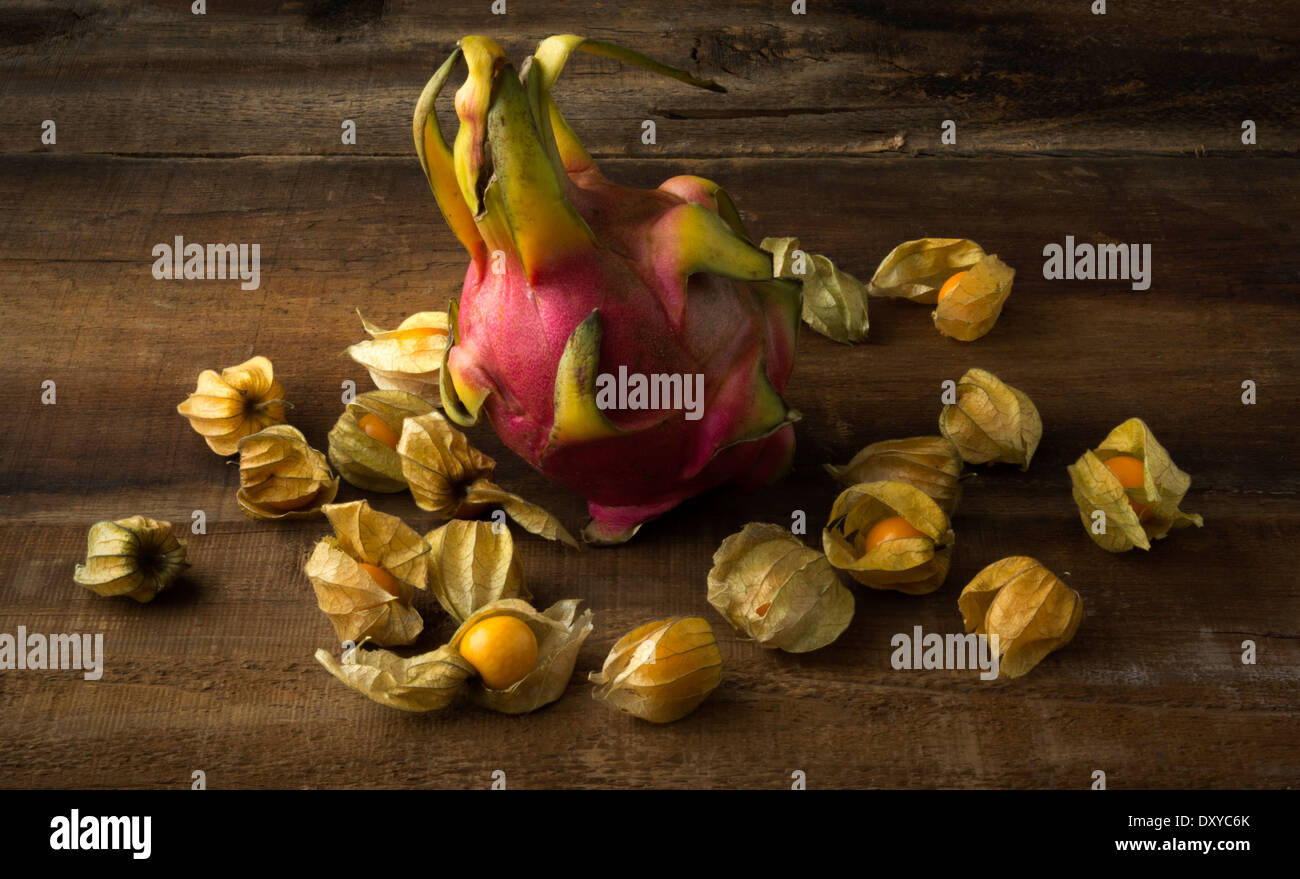 Ganze Drachenfrucht auf Holzbrett umgeben von Stachelbeeren Stockfoto