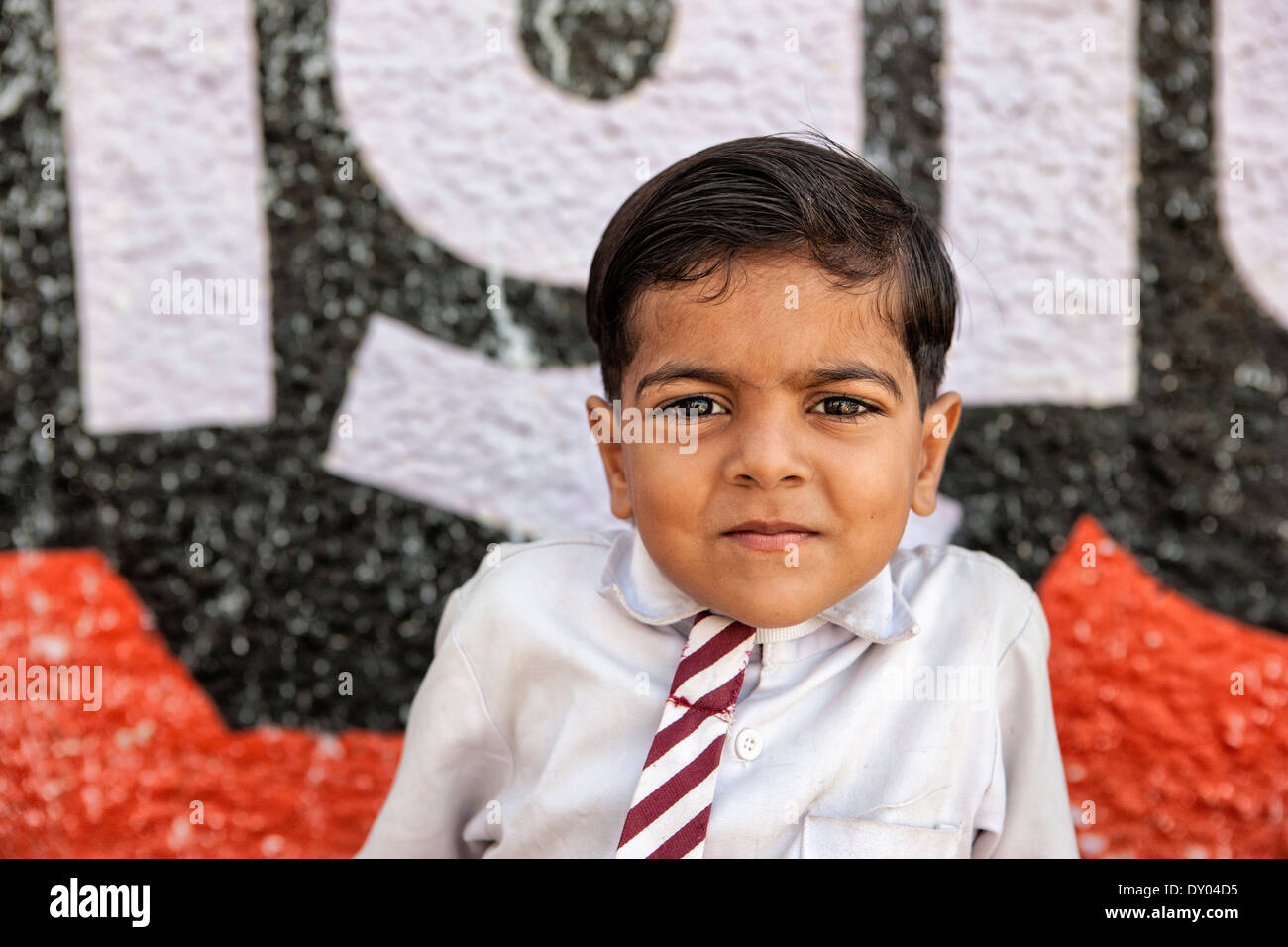 Kind in Pushckar mit einer Schuluniform und eine Krawatte. Hinter ihm eine bizarre Wand Stockfoto