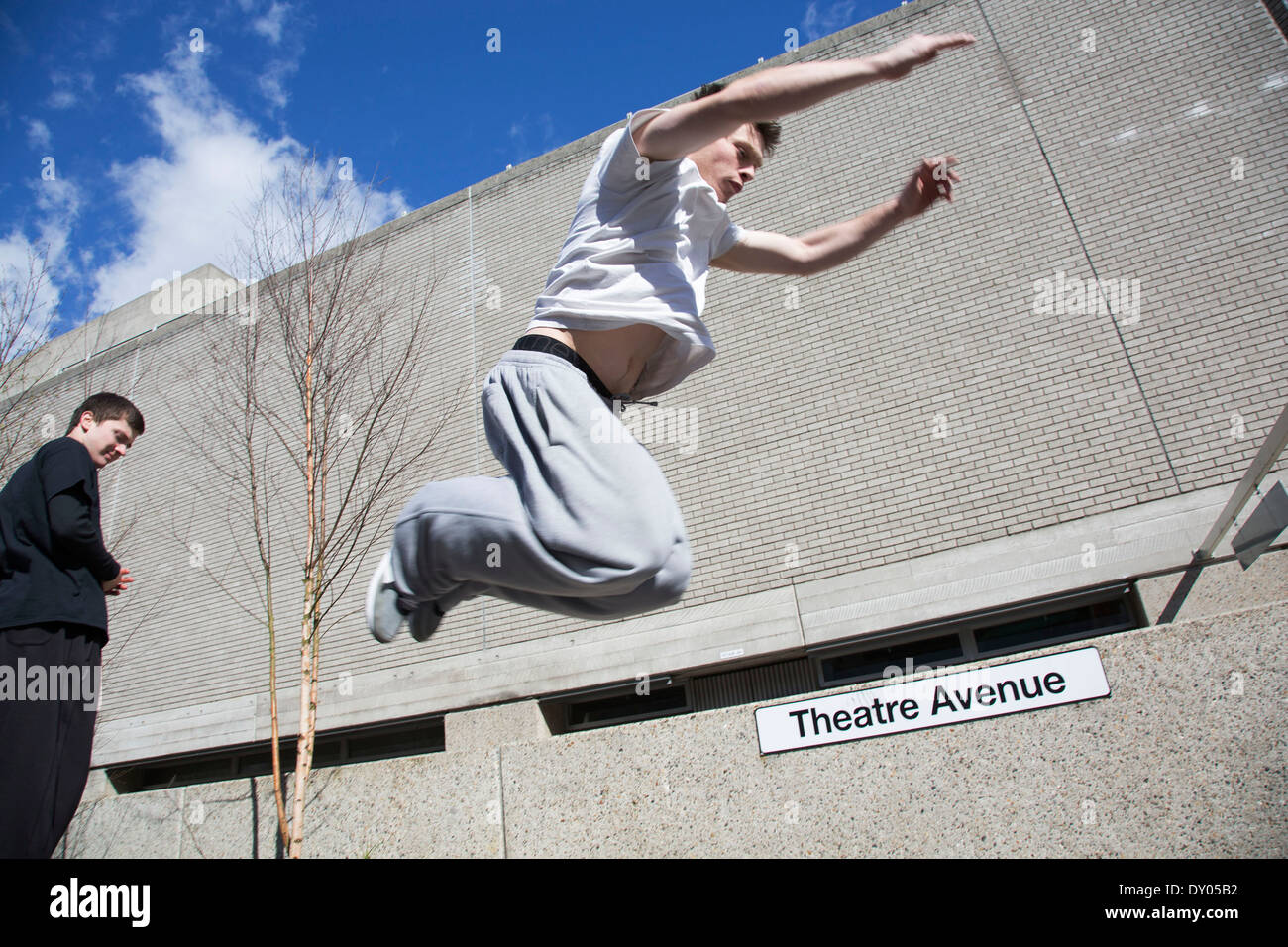 Parkour-Läufer zeigt urban akrobatische Fähigkeiten fliegen kopfüber an der South Bank, London, UK. Stockfoto