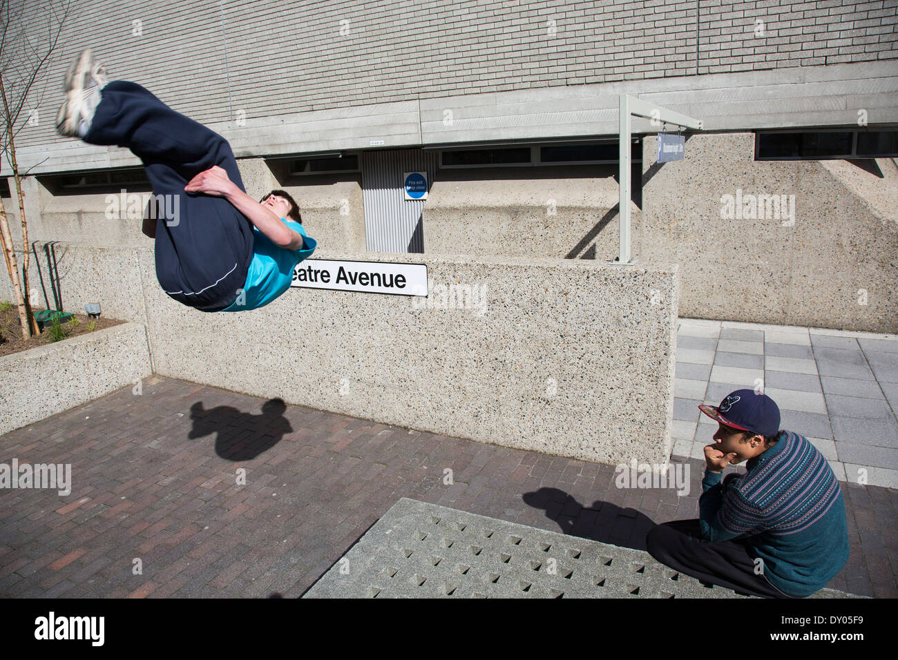 Parkour-Läufer zeigt urban akrobatische Fähigkeiten fliegen kopfüber an der South Bank, London, UK. Stockfoto