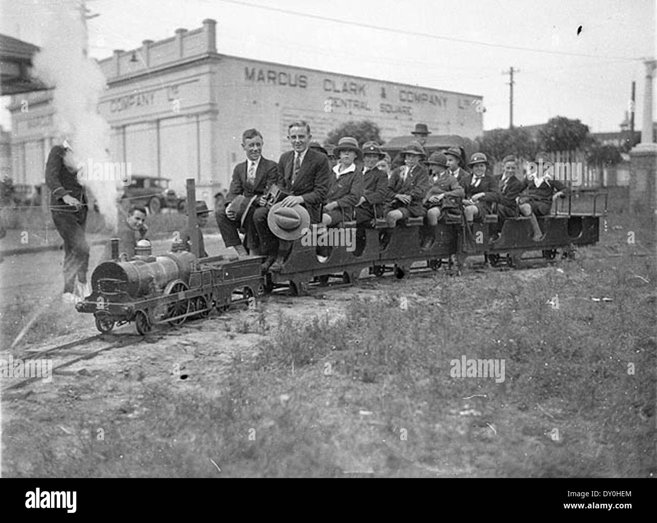 Dieses Foto aus dem Jahr 1927 zeigt Schüler der Fort Street Boys High School, die mit einer Modelldampfbahn fahren. Von Sam Hood aufgenommen, spiegelt er die Faszination der damaligen Zeit für Züge und Modelllokomotiven wider. Stockfoto