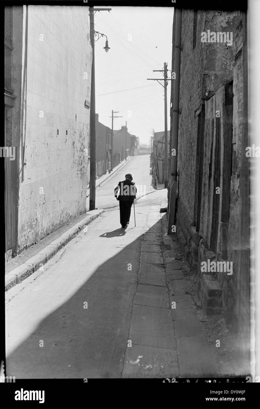 Alter Rentner in Surry Hills Gasse mit Stick, Aug 1949, ab Serie 02: Sydney Menschen & Straßen, 1948-1950, von Brian Vogel fotografiert. Stockfoto