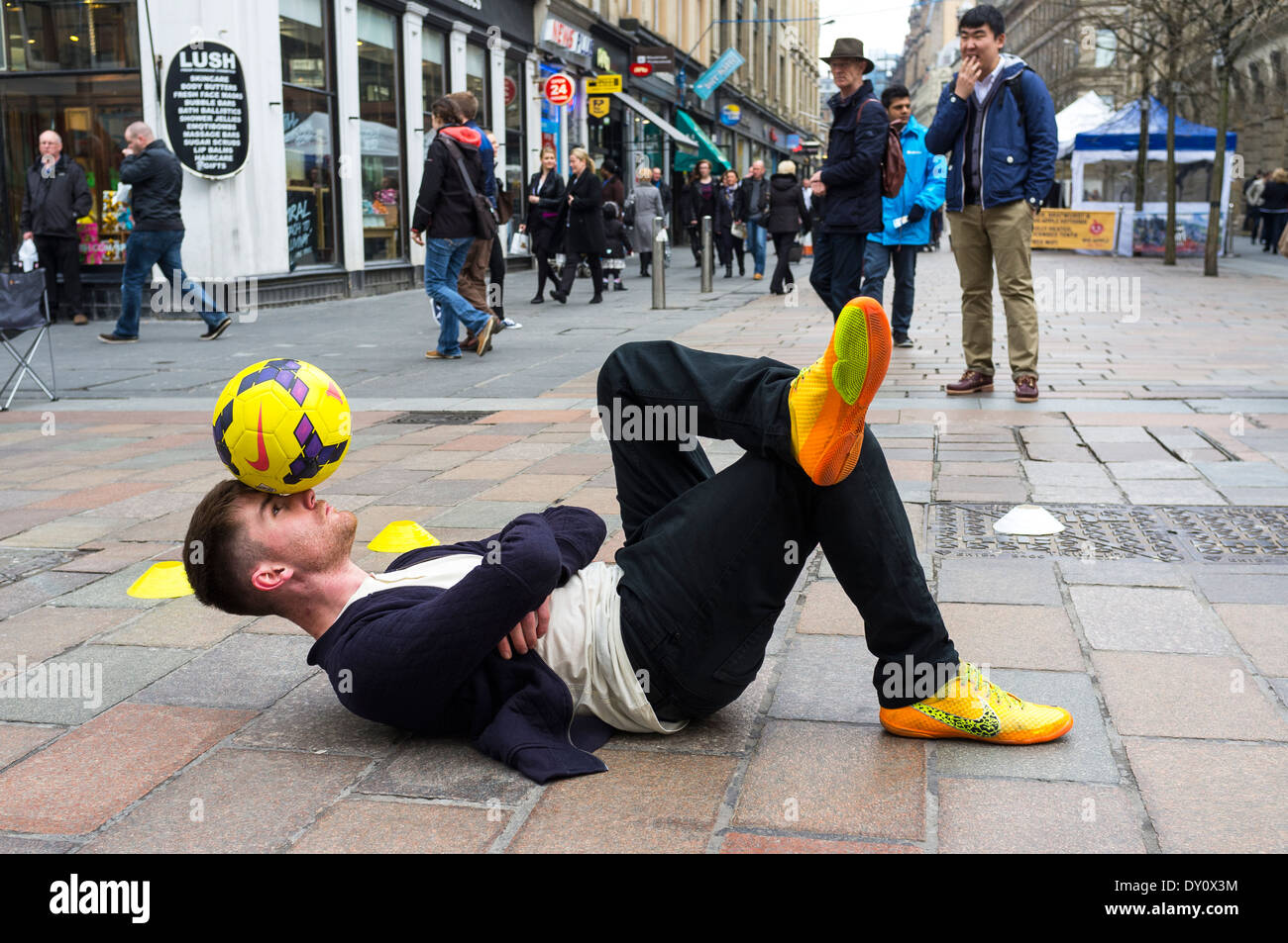 Der Mensch als Straßenmusikant in Buchanan Street, Glasgow, Schottland, Großbritannien. Er trat Ausgleich fungiert und mit einem Fußball tricks Stockfoto