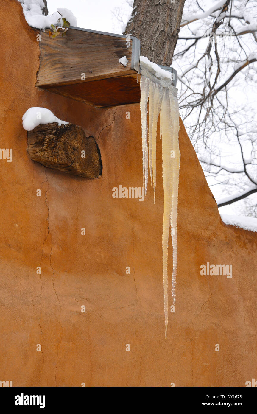 Eiszapfen hängen an einem Canale aus dem Flachdach ein Pueblo Stil Adobe Gebäude an einem Wintertag in Santa Fe, NM Stockfoto