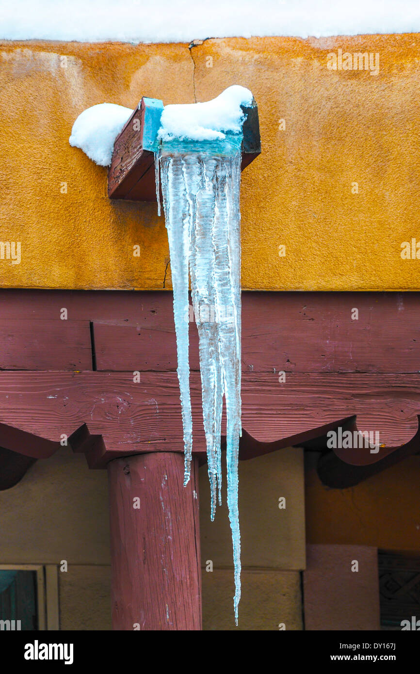 Eiszapfen hängen an einem Canale aus dem Flachdach ein Pueblo Stil Adobe Gebäude an einem Wintertag in Santa Fe, NM Stockfoto