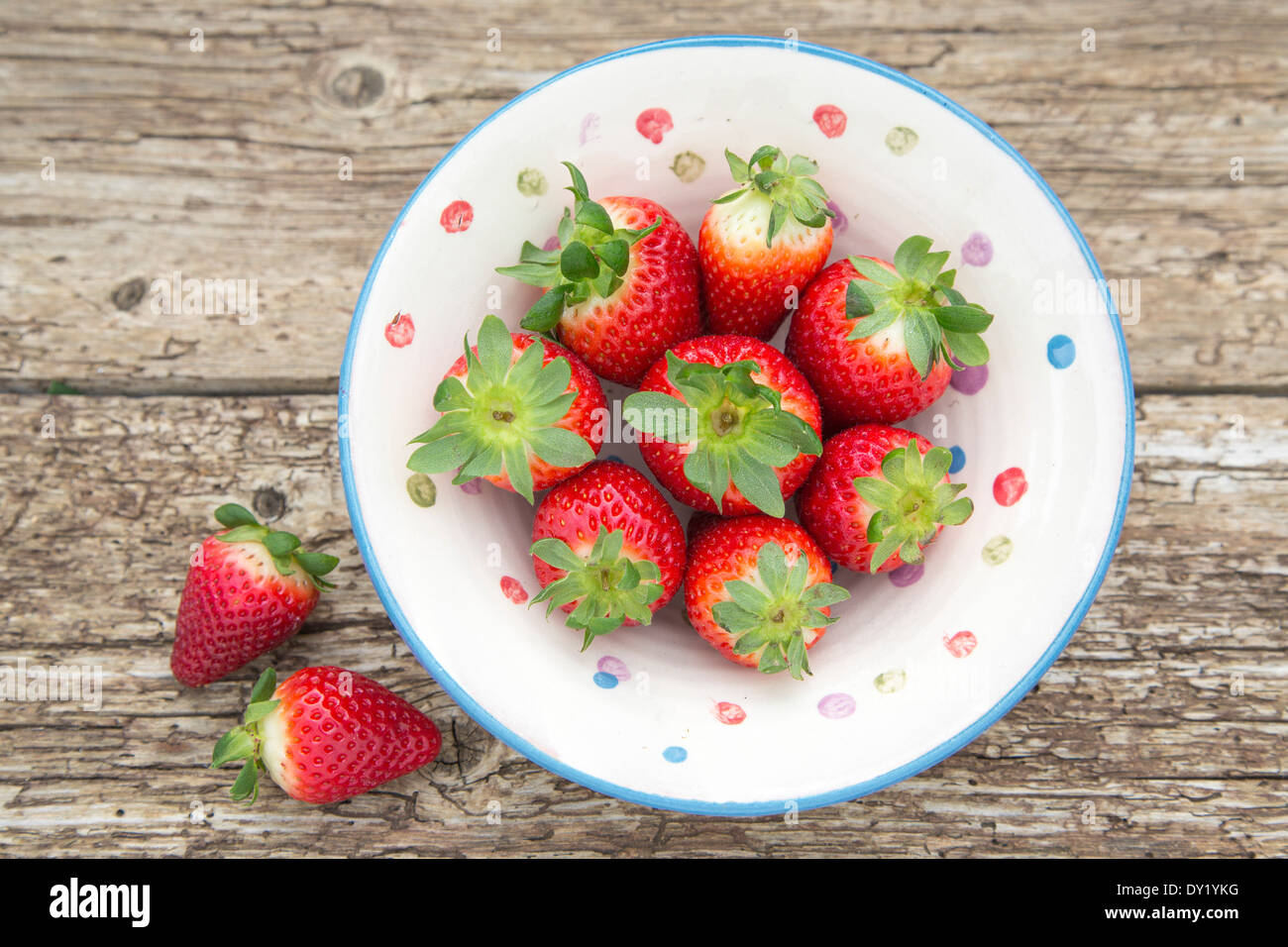 Gesamten spanischen Erdbeeren in einem rustikalen Keramikschale, platziert auf rustikalen Holztisch Stockfoto