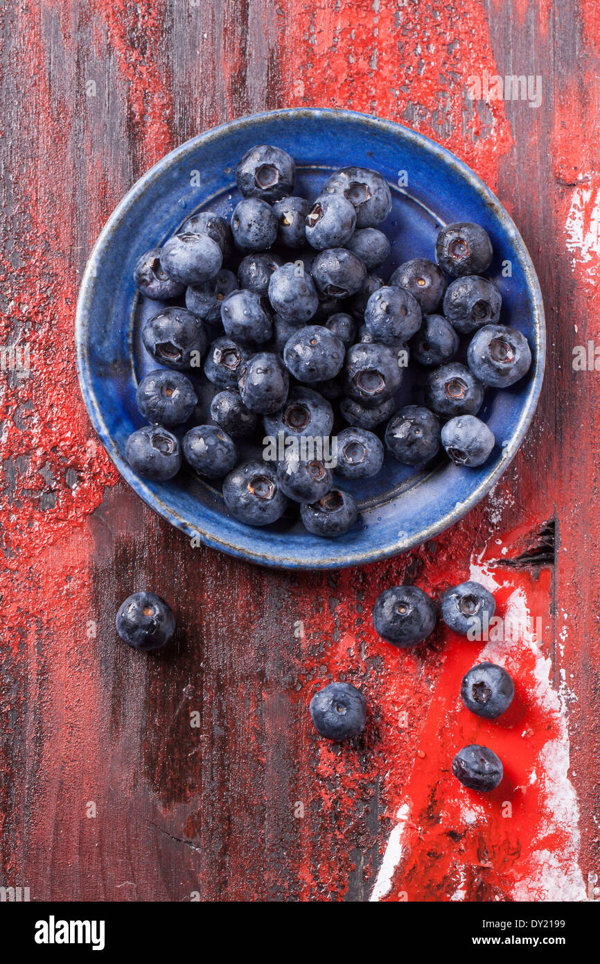 Draufsicht auf blauen Keramikplatte Heidelbeeren über rote Holztisch Stockfoto