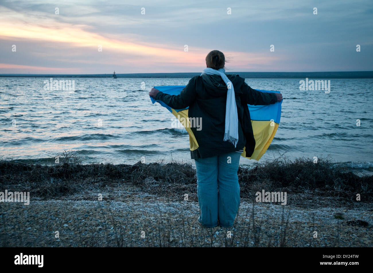 Pro-ukrainische Frau mit einer Nationalflagge steht am Ufer des Donuslaw See, Marines aus U311 Cherkasy Minesweeper zu unterstützen Stockfoto