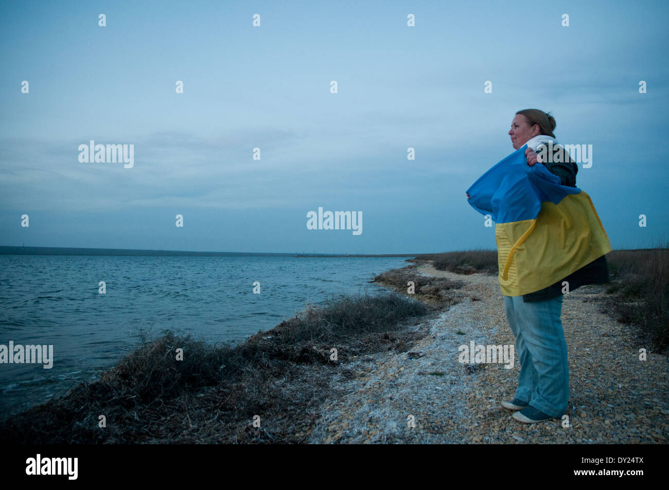 Pro-ukrainische Frau mit einer Nationalflagge steht am Ufer des Donuslaw See, Marines aus U311 Cherkasy Minesweeper zu unterstützen Stockfoto