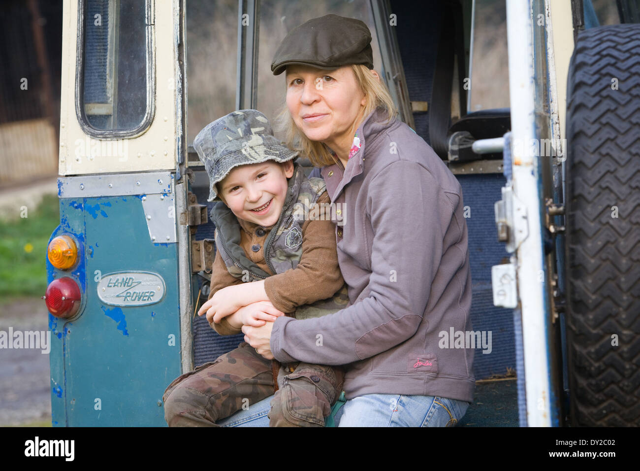Eine Frau saß mit einem 5 Jahre alten Jungen auf der Rückseite ein altes Land Rover Fahrzeug auf dem Lande. Der junge ist ihr Sohn. Stockfoto