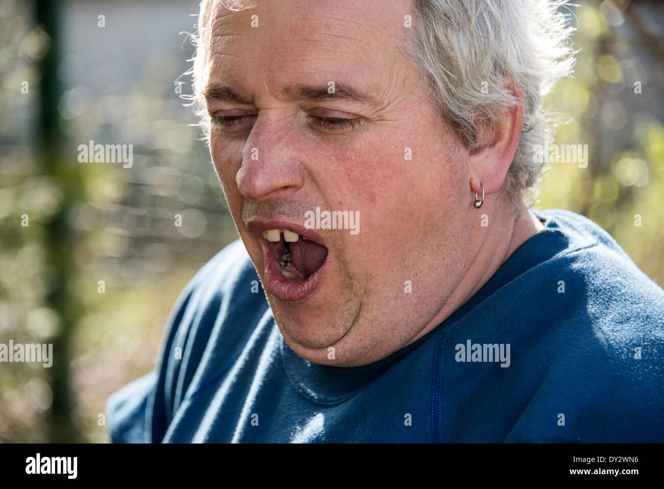 Ein Mann mit grauen Haaren Gähnen Stockfoto