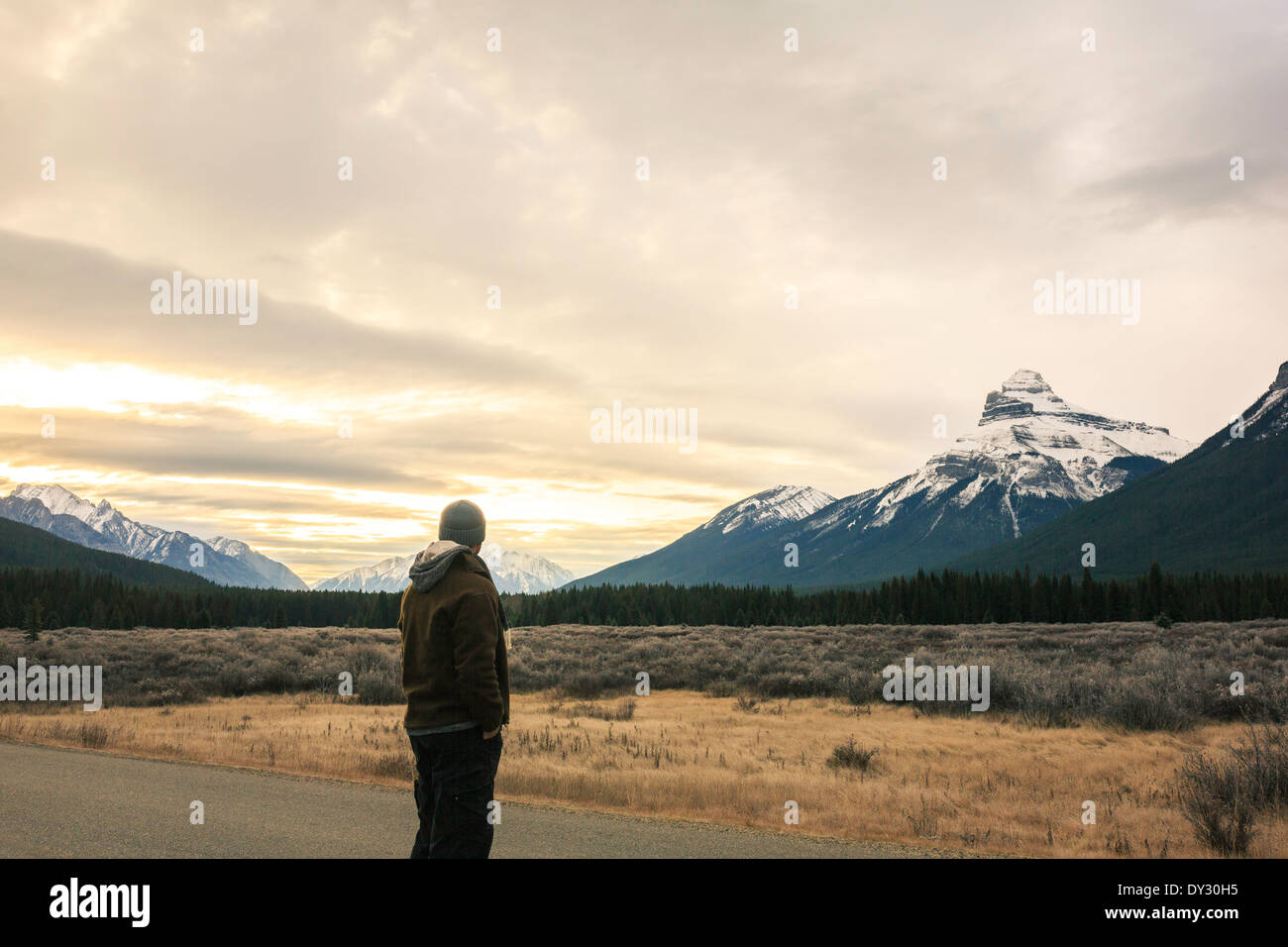 Ein Mann steht an der Seite einer Straße genießen den Sonnenaufgang in den Rocky Mountains in Kanada. Stockfoto