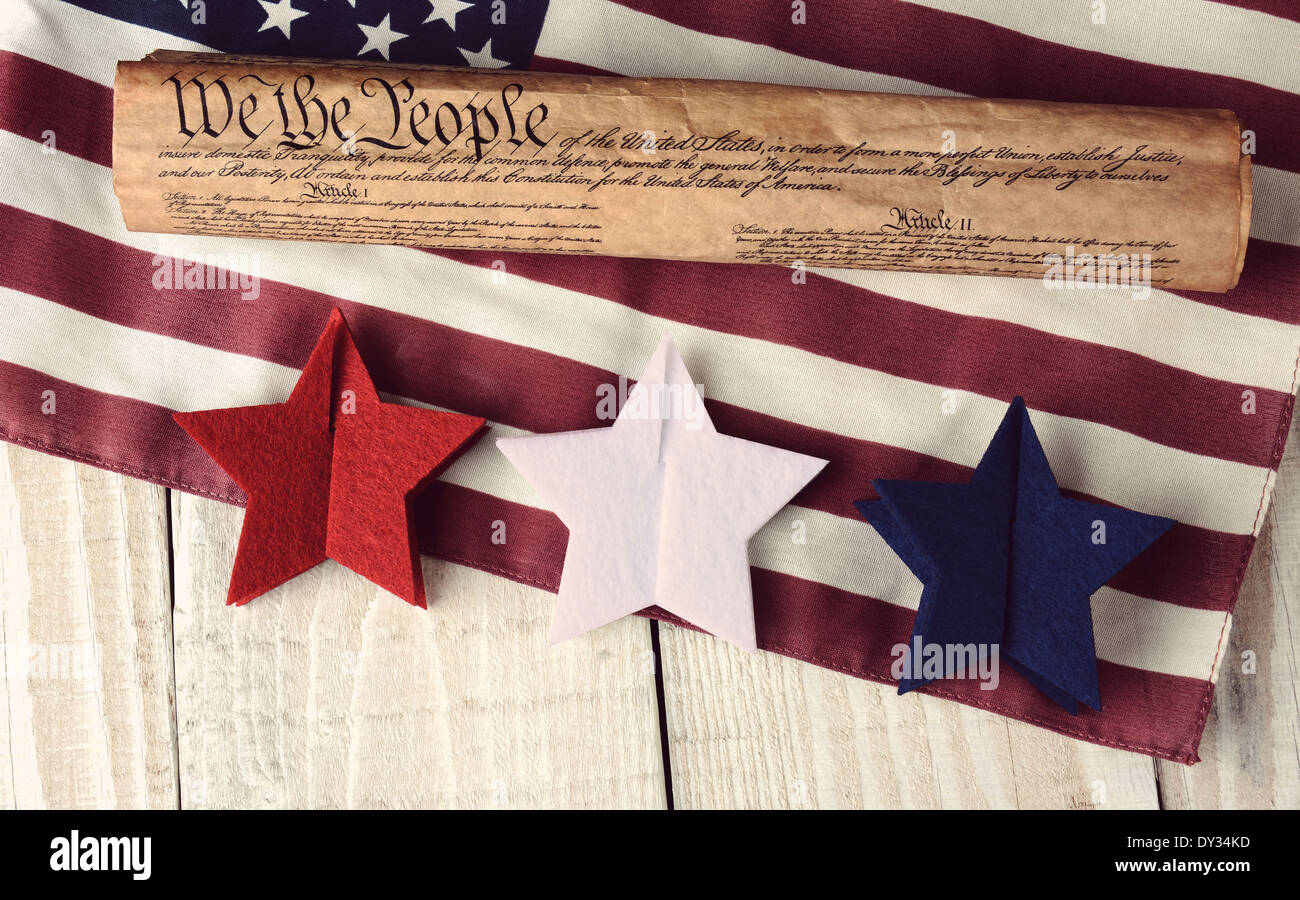 Ein Rollup US-Verfassung auf eine amerikanische Flagge mit roten, weißen und blauen Sternen im Vordergrund. Hohen Winkel am rustikalen Tisch erschossen Stockfoto