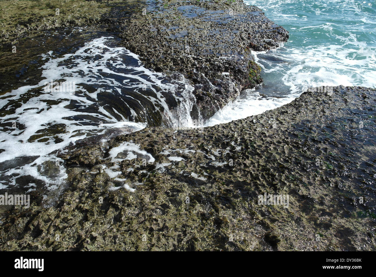 Meerwasser stürzt gegen Felsen an der Küste, wo eine Höhle gebildet wird Stockfoto