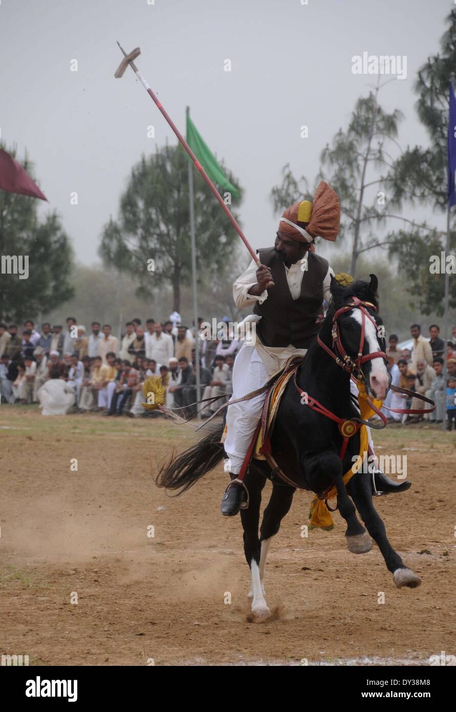 PAKISTAN, Islamabad-April 05:A pakistanische Reiter tragen Trachten (Shalwar Kameez und traditionellen Turban auf dem Kopf) trifft sein Ziel als er an einer dreitägigen Zelt pegging bzw. Neza-Bazi traditionelle Wettbewerb nimmt anlässlich der Einführung des "Jashn-e-Baharan" oder Frühlingsfest in Islamabad am 5. April 2014. Teilnehmer des Zeltes pegging Spiel versuchen zu treffen und den Boden mit einem Speer der genagelten Holzklotz ausziehen. Spieler beginnen, ihre Pferde laufen und versuchen, das Ziel zu treffen, und holen Sie es mit Lanze. Bildnachweis: Pazifische Presse/Alamy Live-Nachrichten Stockfoto