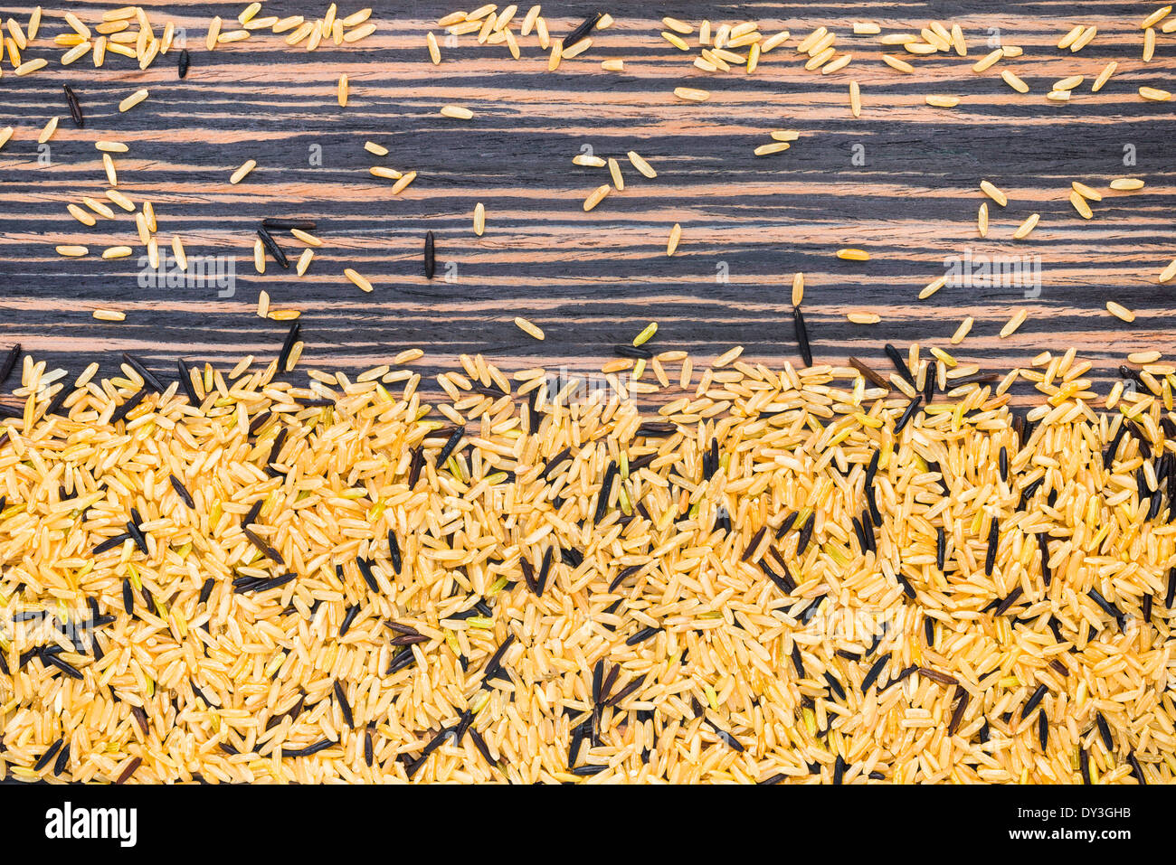 Braun und wild Trockenreis auf einem Zebrano-Holz-Hintergrund Stockfoto