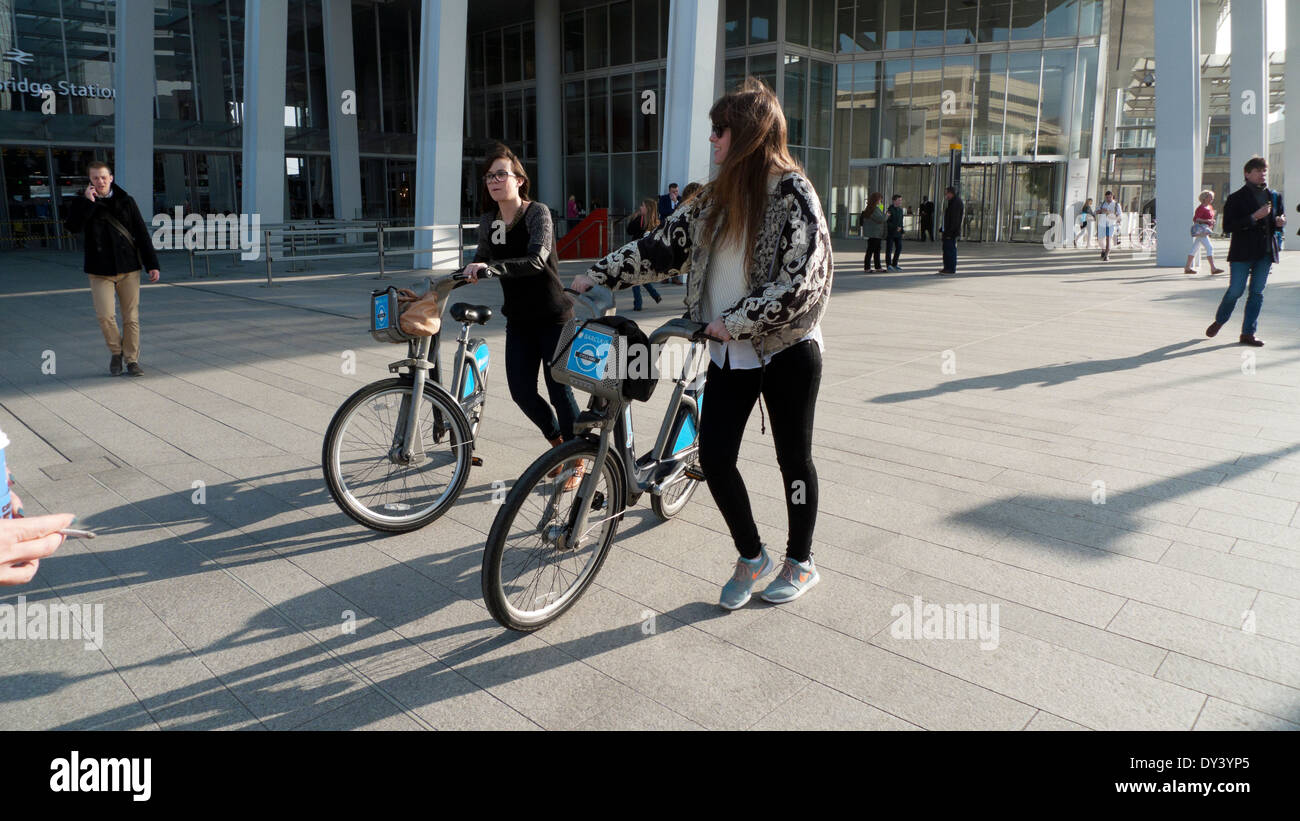 Junge Frauen Radfahrer zu Fuß mit Boris Bikes an der Basis des Shards in London, UK KATHY DEWITT Stockfoto