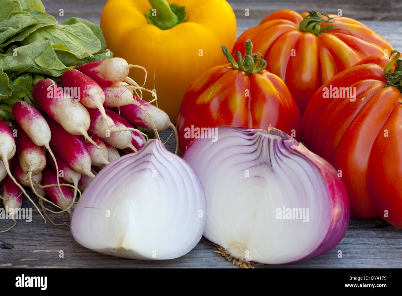 Coeur de Boeuf Tomaten, große rote Zwiebeln und Radieschen frisch vom Wochenmarkt auf einem alten Holztisch Stockfoto