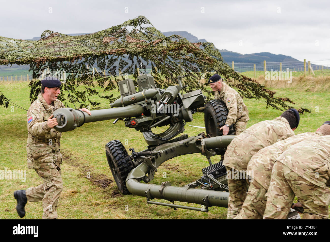 Soldaten aus der Royal Artillery Lift ein 105mm Artillerie Lightgun ermöglicht ein Kollege, eine Rad zu entfernen Stockfoto