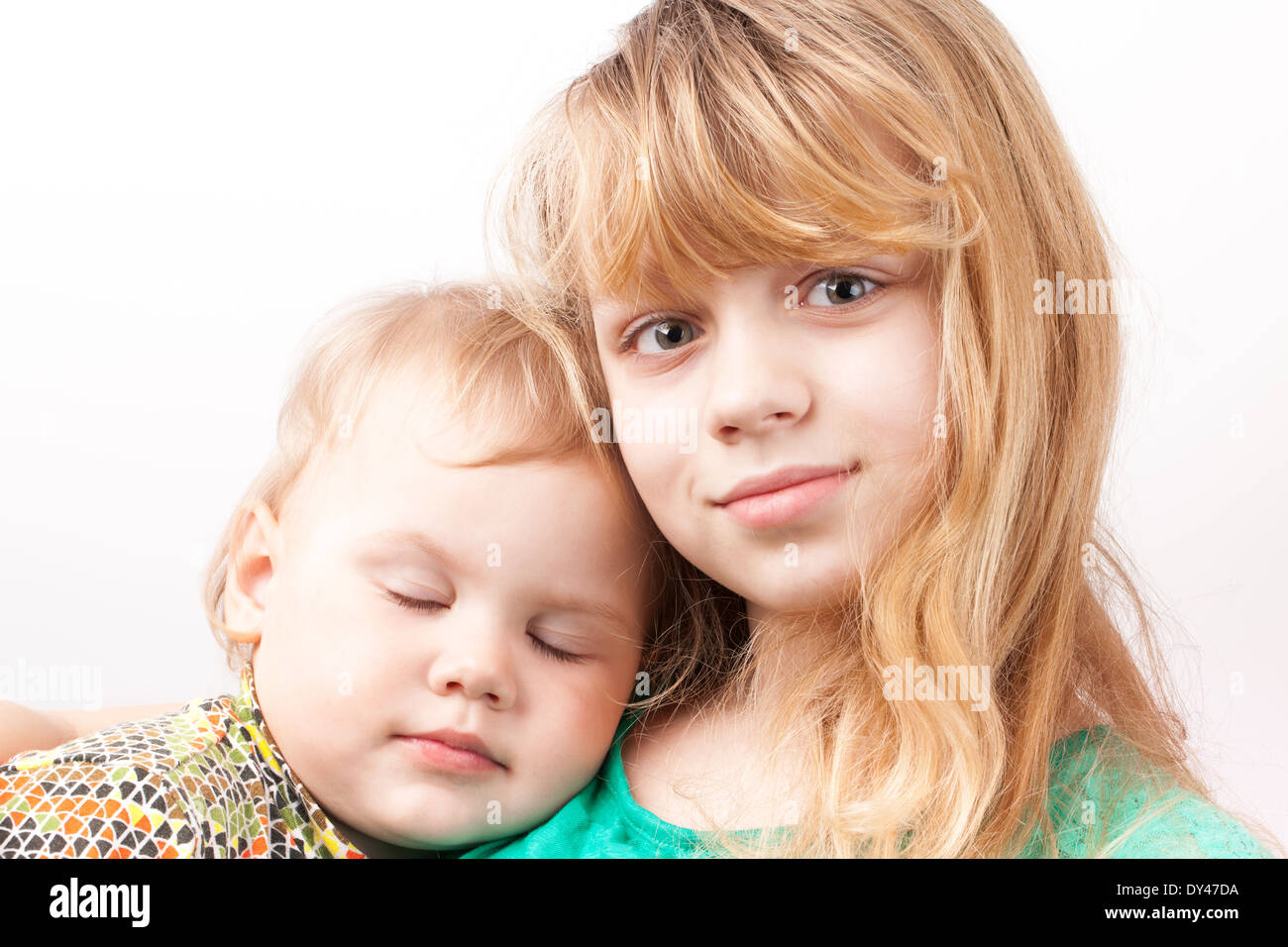 Kleine blonde kaukasische Mädchen mit schlafenden Schwester. Porträt auf weißem Hintergrund Stockfoto