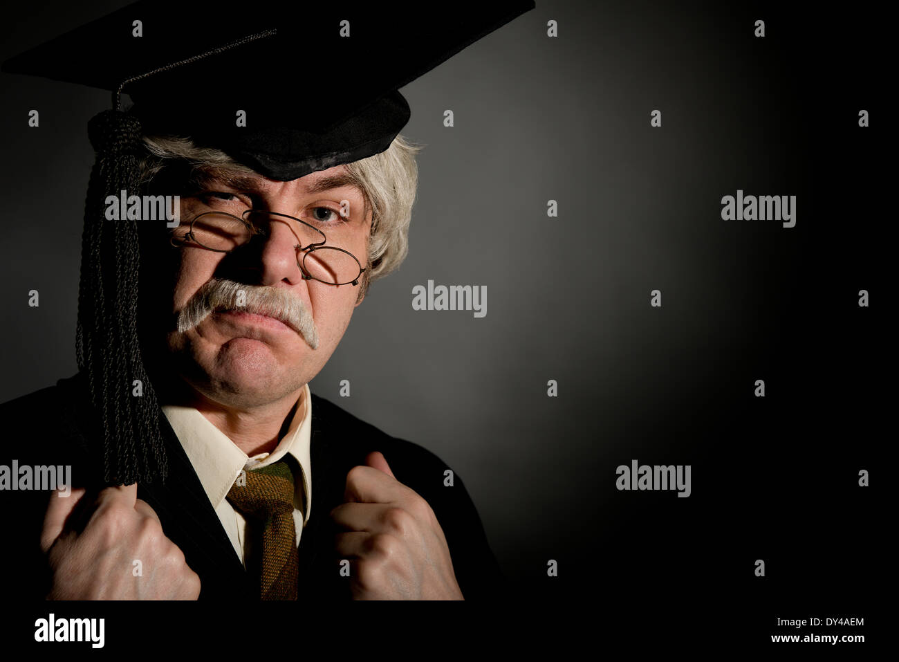 Mürrisch, alten Stil englischer Schulleiter mit Doktorhut, vielfarbig schwarzen Hintergrund. Stockfoto