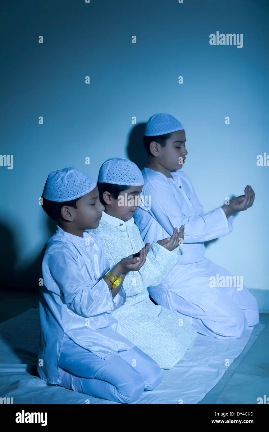 Indische muslimische Kinder sitzen und Prayering Stockfoto