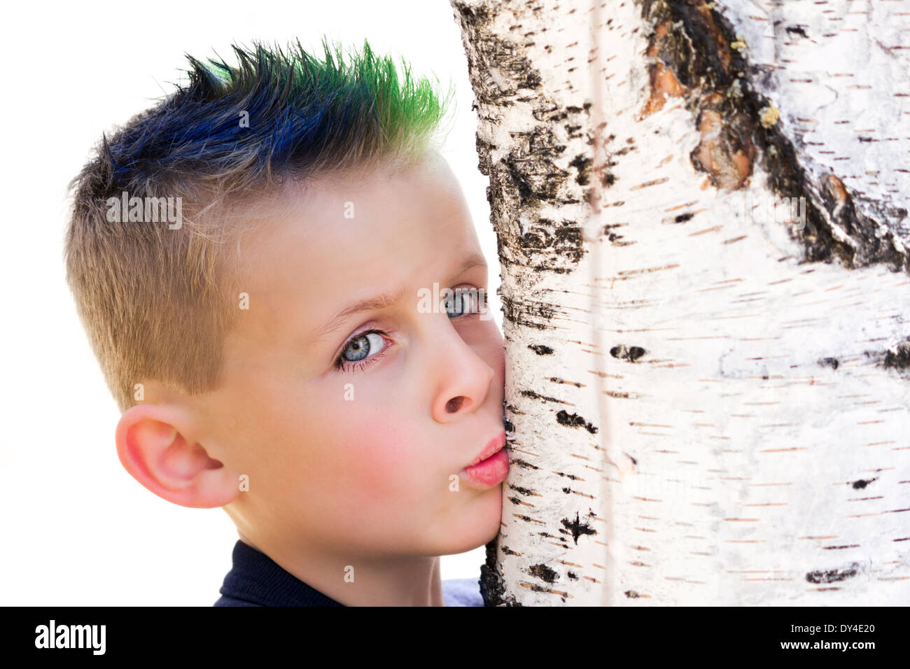 Kleiner Junge mit blauen und grünen spikey Haar küssen einen Birke Baumstamm Stockfoto