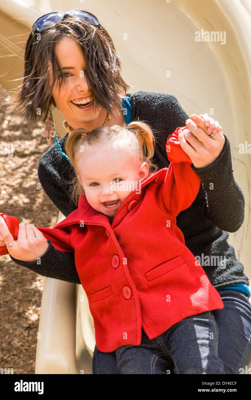 Schöne junge Mutter mit 16 Monate Baby Girl auf Park Spielplatz spielen Stockfoto