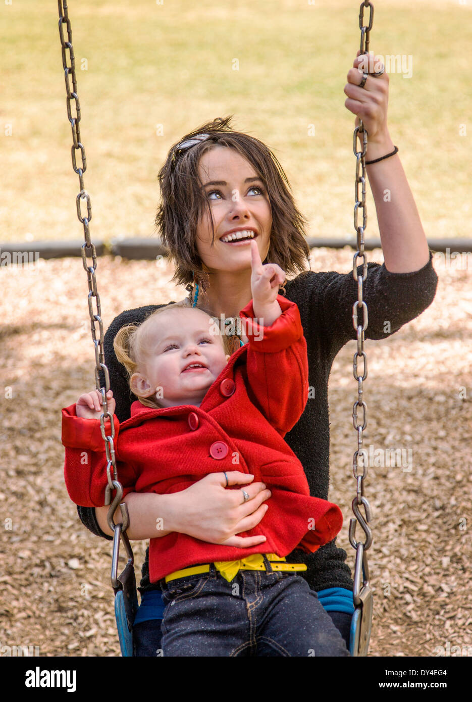 Schöne junge Mutter auf Park Spielplatz Schaukeln mit liebenswert, niedlich 16 Monate Babymädchen spielen Stockfoto