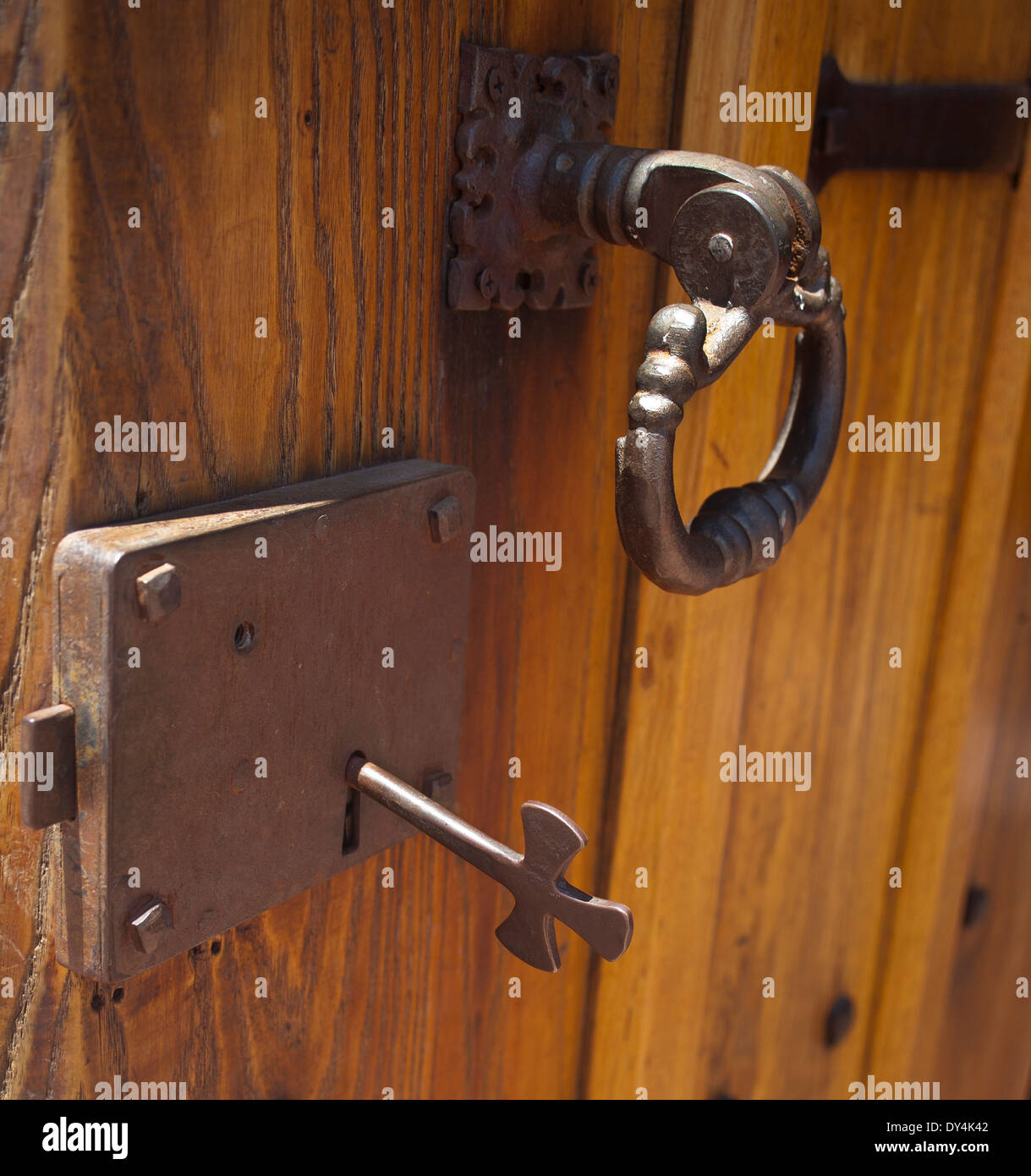 Holztür mit Vintage Metall Türgriff und Schloss mit dem Schlüssel in das Schlüsselloch. Schlüssel hat ein Kreuz drauf Stockfoto