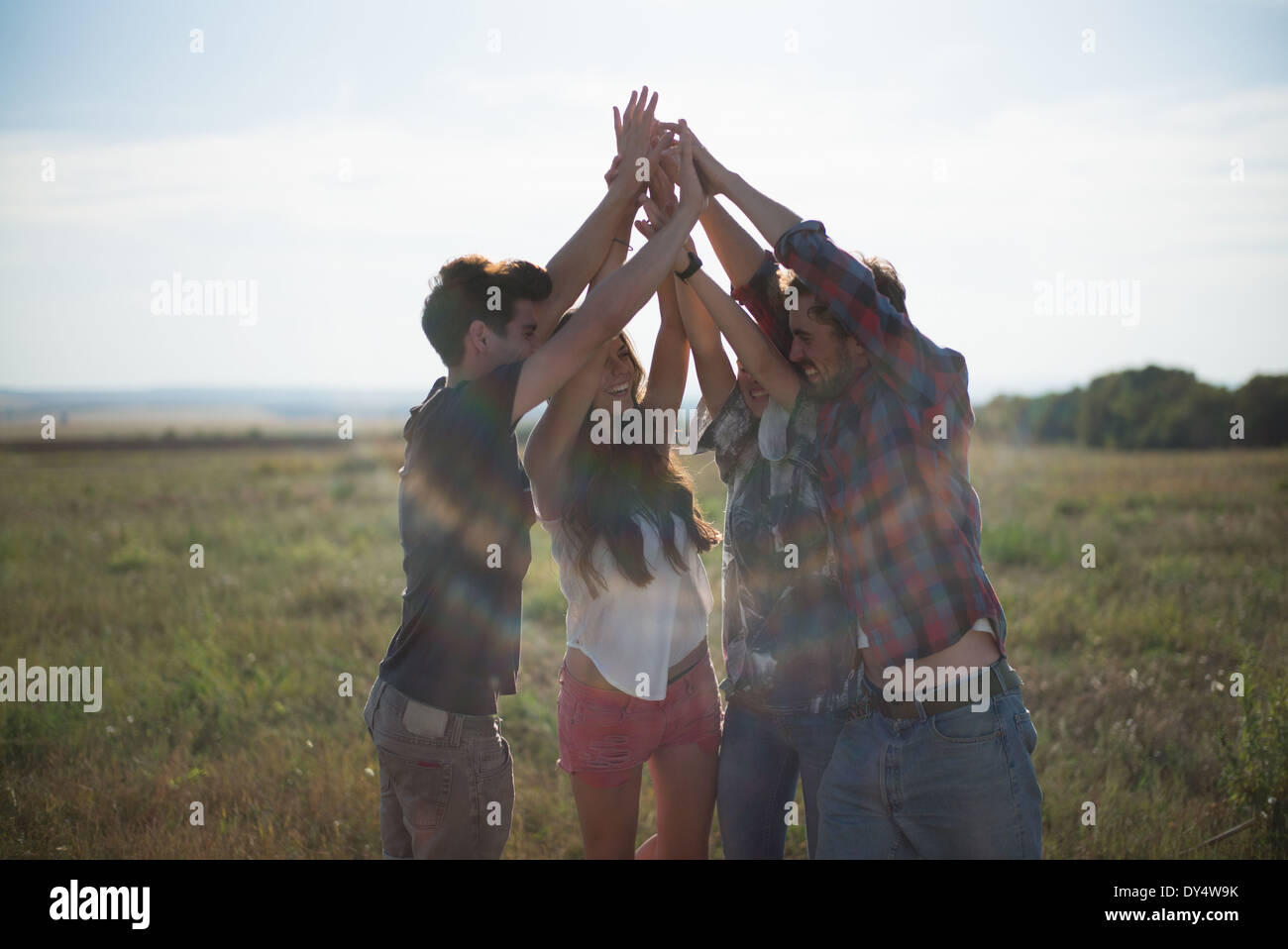 Vier Freunde Hand in Hand mit erhobenen Armen Stockfoto