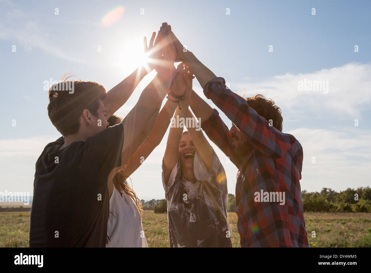 Vier Freunde Hand in Hand mit erhobenen Armen Stockfoto
