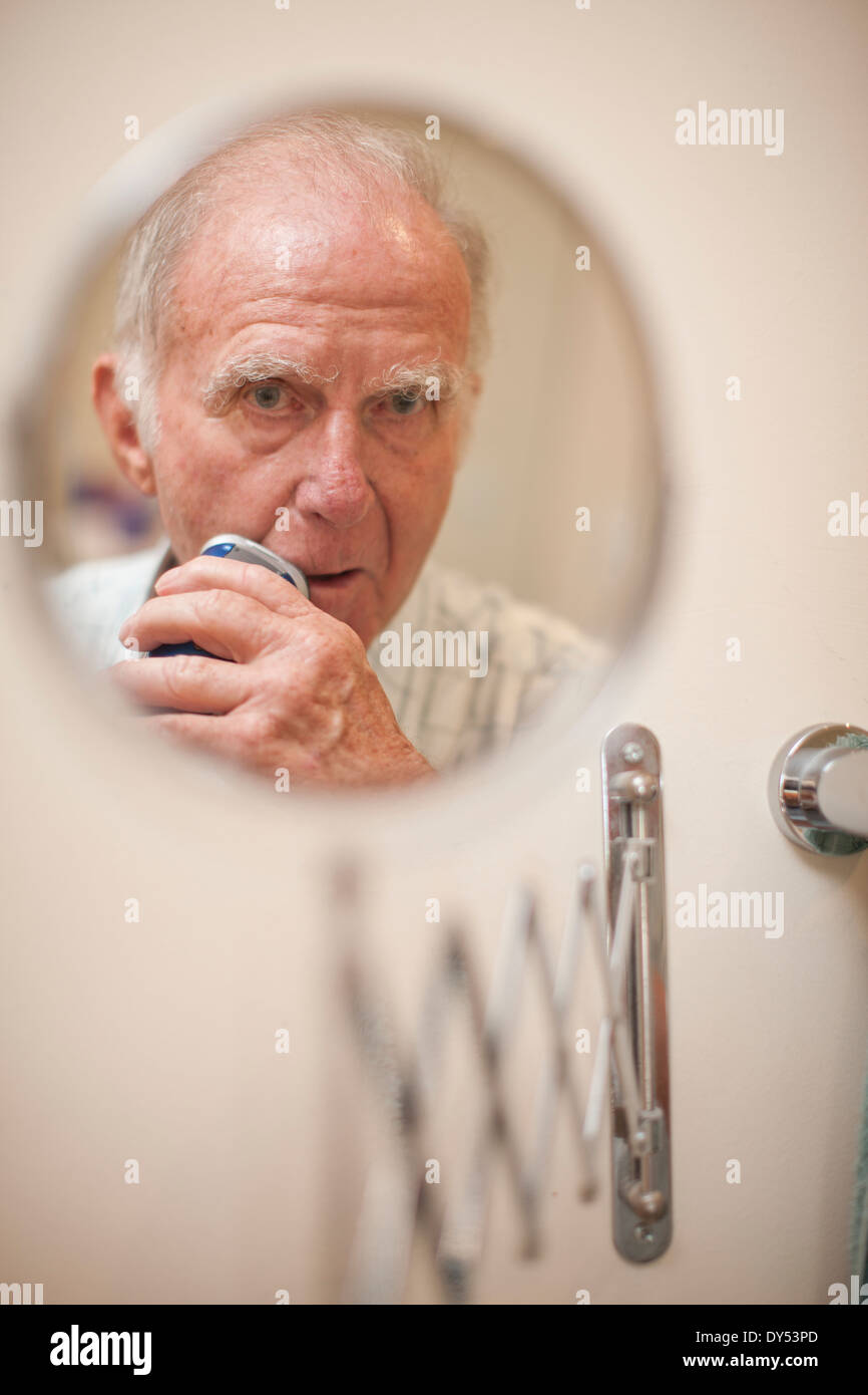 Porträt von senior woman in Rasier-Spiegel mit Elektrorasierer Stockfoto