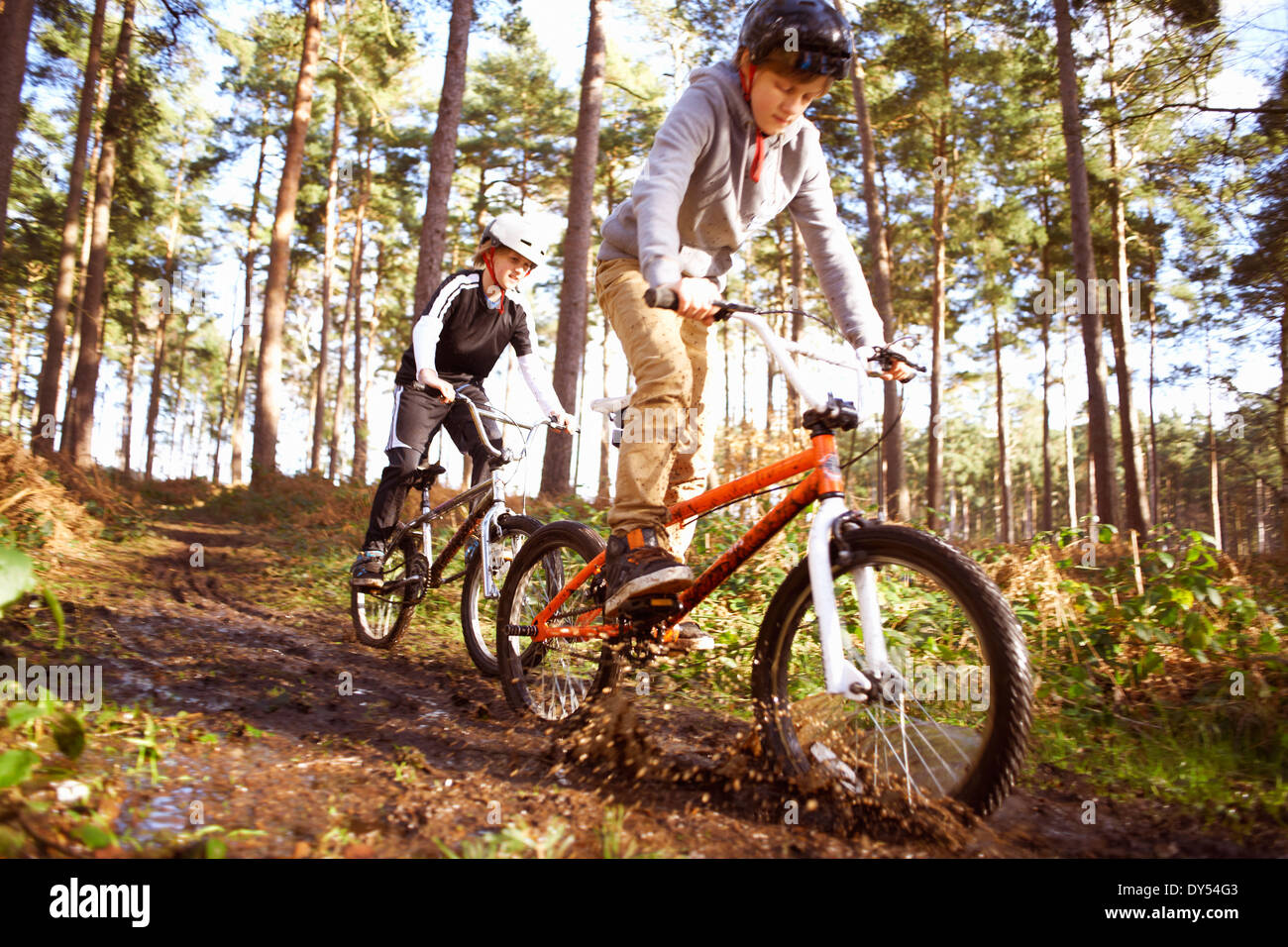 Zwillingsbrüder BMX Rennrad durch schlammigen Wald Stockfoto