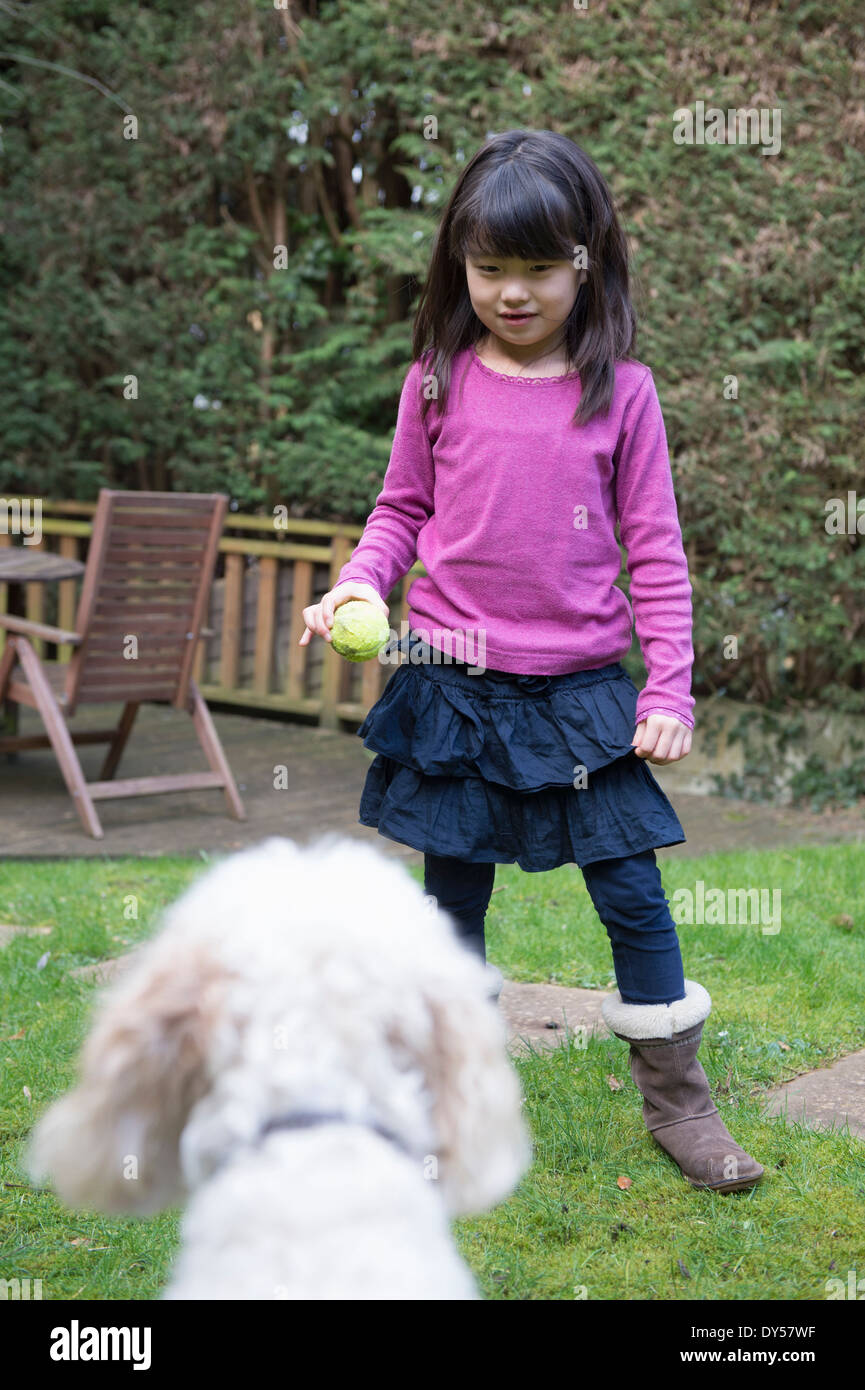 Mädchen spielen Ball mit ihrem Hund im Garten Stockfoto